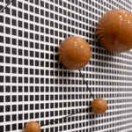 Contemporary abstract wall art featuring suspended terracotta spheres in graduated sizes against geometric gridded backdrop, modern interior