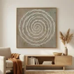 Textured abstract hand-painted canvas featuring concentric white spiral brushstrokes on muted taupe ground, contemporary living space