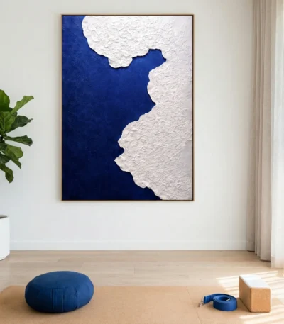 Minimalist hand-painted canvas with textured white coastline against deep navy blue, contemporary studio space