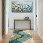 Abstract hand-painted canvas of delicate white blossoms with gold accents against soft blue tones, contemporary entryway