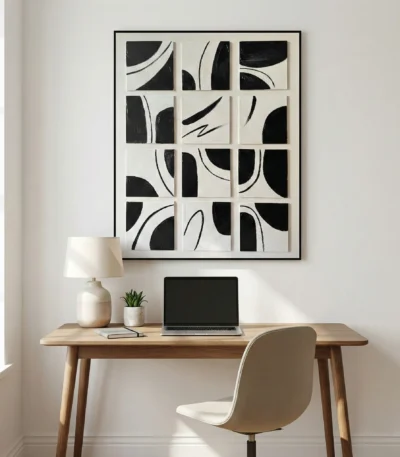 Minimalist abstract hand-painted canvas with bold black curved forms and gestural lines in monochrome, contemporary workspace