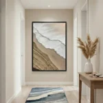 Minimalist hand-painted canvas depicting aerial beach waves and sand in soft cream and grey tones, entryway setting