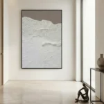 Textured abstract landscape painting in cream and white with layered gestural brushstrokes, displayed in contemporary minimalist space
