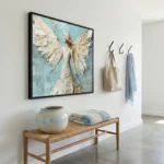 Textured hand-painted canvas of an ethereal winged figure in cream and gold against soft blue, contemporary entryway
