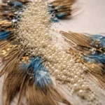 Textured hand-painted canvas with cream pearl beads, bronze brushstrokes, and teal accents on neutral linen