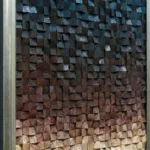 Textured abstract wall art with hand-painted wooden blocks in gradient tones from charcoal to warm walnut, contemporary interior
