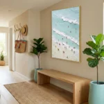 Impressionist aerial beach painting depicting turquoise waters and swimmers in soft cream and aqua tones, hand-painted canvas in contemporary entryway