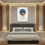 Contemporary abstract hand-painted canvas with geometric shapes in navy, orange, and speckled cream tones, modern bedroom