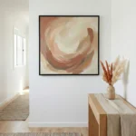 Gestural abstract hand-painted canvas in warm terracotta, cream, and ochre tones with swirling brushwork, contemporary entryway