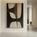Minimalist hand-painted canvas with organic curved forms in cream, charcoal, and brown tones, contemporary gallery space