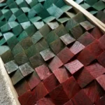 Textured abstract hand-painted canvas with layered geometric squares in cool greens transitioning to warm deep reds and burgundy tones