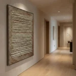 Textured abstract hand-painted canvas with layered horizontal striations in metallic gold and cream tones, contemporary hallway