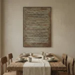 Textured abstract hand-painted canvas with horizontal linear relief marks in warm metallic gold and cream tones, contemporary dining space