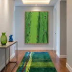 Textured abstract hand-painted canvas with vibrant lime green and gestural brushstrokes depicting figure silhouettes, contemporary hallway