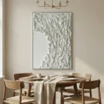 Textured abstract hand-painted canvas in monochromatic white and cream with gestural relief movements, contemporary dining space
