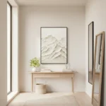 Textured monochrome landscape painting depicting layered mountains in cream and white tones, hand-painted canvas in minimalist hallway