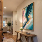 Layered abstract hand-painted canvas in teal, gold, and pink fluid swirls, contemporary entryway