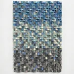 Textured abstract hand-painted canvas with layered dimensional squares in cool blues, greens, and neutral tones, contemporary living space