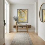 Gestural abstract hand-painted canvas with sweeping golden brushstrokes on cream background, contemporary entryway