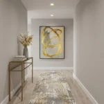 Gestural abstract hand-painted canvas with looping gold brushstrokes on cream and grey, contemporary hallway setting
