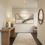 Layered abstract hand-painted canvas in soft blush, charcoal and gold flowing brushstrokes, modern entryway