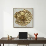 Textured gold leaf hand-painted canvas depicting a blooming peony in cream and ochre tones, contemporary workspace
