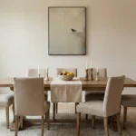 Minimalist hand-painted canvas depicting a solitary bird perched on sand in muted beige and grey tones, contemporary dining space