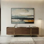 Layered abstract hand-painted canvas in muted ocean blues, warm ochre, and charcoal tones, contemporary living space