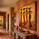 Figurative hand-painted canvas depicting four African women in red and blue garments against warm golden-yellow background, hallway display