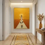 Figurative hand-painted canvas depicting a woman and children walking toward golden sunset over water in warm ochre tones, contemporary hallway