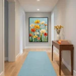Impressionist hand-painted canvas of vibrant yellow, orange and cream gerbera daisies with green stems against soft blue sky, hallway setting