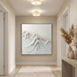 Textured monochrome hand-painted canvas depicting snow-capped mountain peaks in layered white and gray tones, contemporary entryway