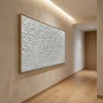 Textured hand-painted canvas depicting a solitary tree with delicate dispersing foliage in monochromatic white and grey tones, contemporary hallway