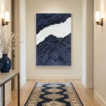 Textured abstract hand-painted canvas depicting layered navy and white mountain forms with gestural brushwork, contemporary entryway