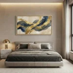 Gestural abstract hand-painted canvas with flowing navy and gold leaf brushstrokes on cream ground, modern bedroom