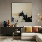 Abstract expressionist hand-painted canvas in monochrome black, cream, and ochre with gestural brushstrokes, contemporary living space