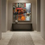 Impressionist hand-painted canvas depicting rainy city street with glowing storefronts and yellow taxi, warm amber and grey palette, contemporary gallery setting