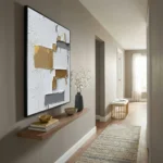 Textured abstract hand-painted canvas with layered white, gold, and charcoal patches in contemporary hallway
