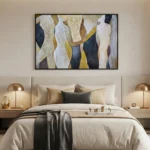 Layered abstract hand-painted canvas in cream, gold, and charcoal with organic flowing forms, modern bedroom setting
