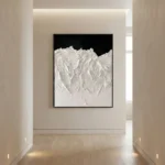 Textured abstract hand-painted canvas depicting snow-capped mountain peaks in white and cream against black, contemporary gallery space