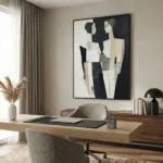 Abstract hand-painted canvas with layered geometric figures in black, cream, and taupe tones, contemporary office