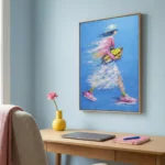 Gestural hand-painted canvas depicting a figure in pink and yellow with flowing brushwork against vibrant blue, modern workspace