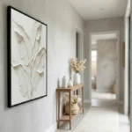Textured minimalist hand-painted canvas depicting botanical leaves in cream and white impasto, hallway setting
