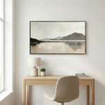 Minimalist landscape hand-painted canvas depicting misty mountains and still water in muted grays and creams, styled in contemporary workspace
