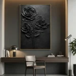 Textured monochrome hand-painted canvas depicting three roses in dramatic relief, black tones on charcoal ground, contemporary workspace