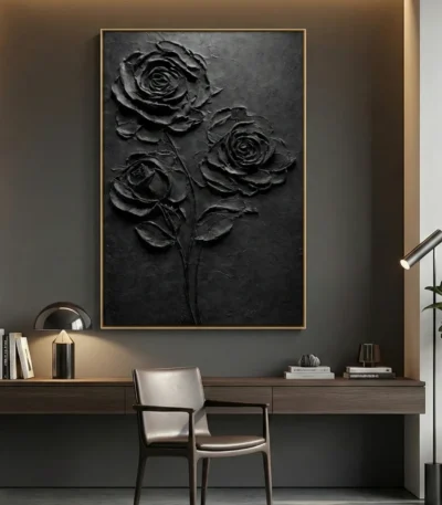 Textured monochrome hand-painted canvas depicting three roses in dramatic relief, black tones on charcoal ground, contemporary workspace