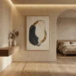 Minimalist hand-painted canvas featuring an abstract organic form in black and gold leaf on cream, contemporary bedroom setting