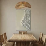 Textured abstract hand-painted canvas with layered white relief forms and organic gestural marks in monochromatic tones, contemporary dining space