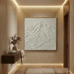 Textured monochrome hand-painted canvas depicting layered mountain peaks in white and cream tones, contemporary entryway
