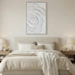 Textured monochrome hand-painted canvas of an abstracted rose in soft white relief, contemporary bedroom